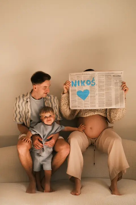 Rodzina z synkiem czyta gazetę z napisem „It's a boy”